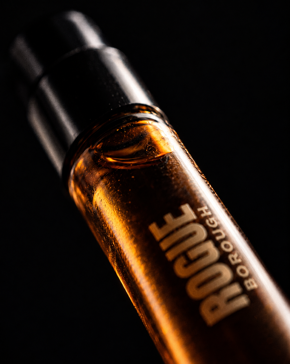Macro shot of a ROGUE Borough 2 ml amber eau de parfum vial